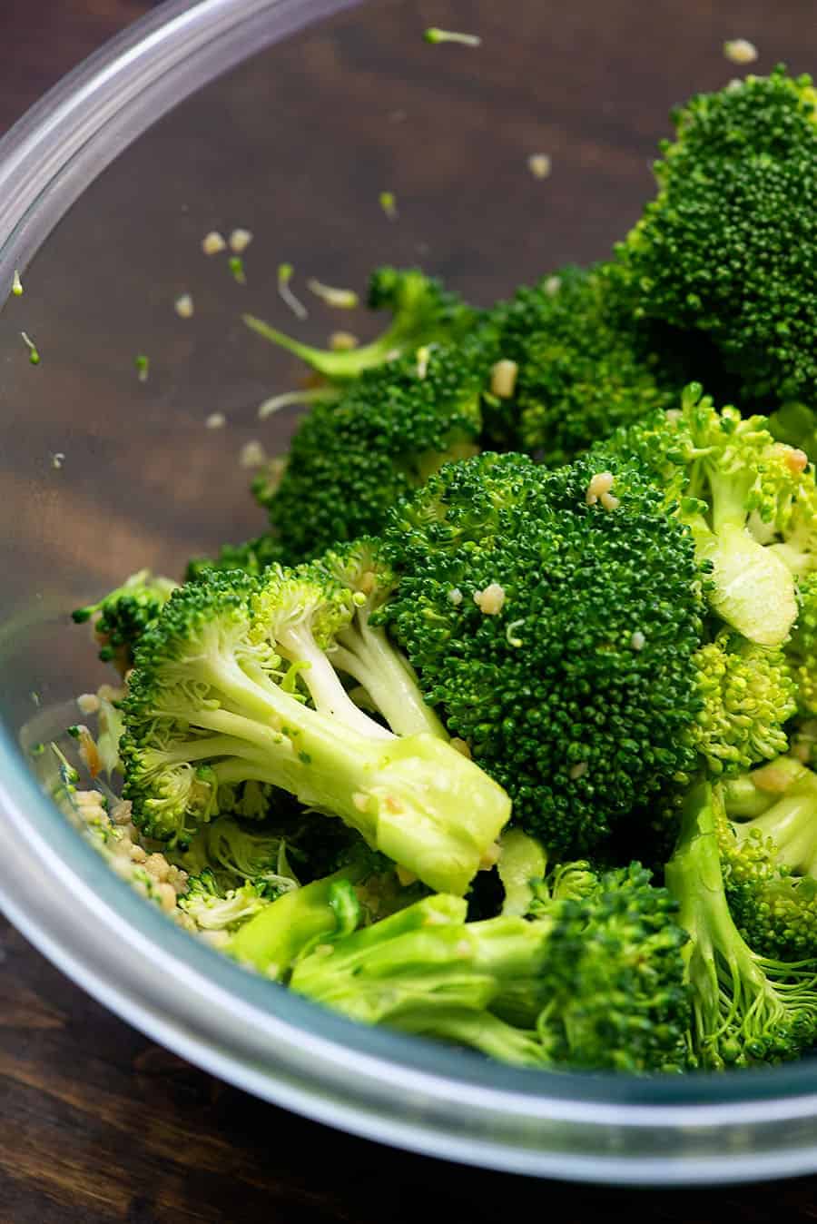 seasoned broccoli to roast in a glass bowl