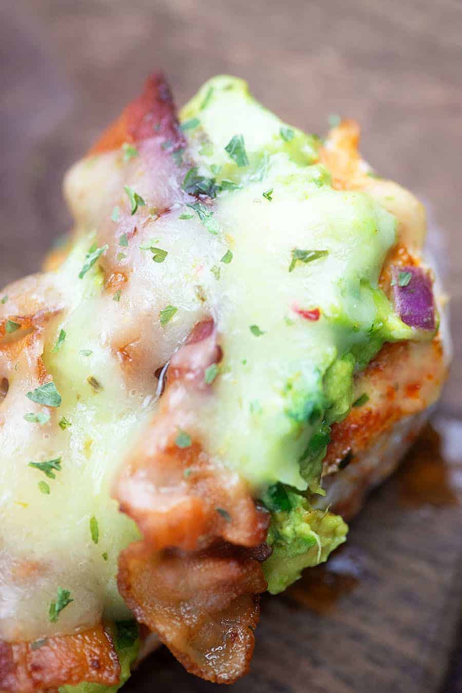 Chicken topped with melted cheese, bacon, and guacamole 