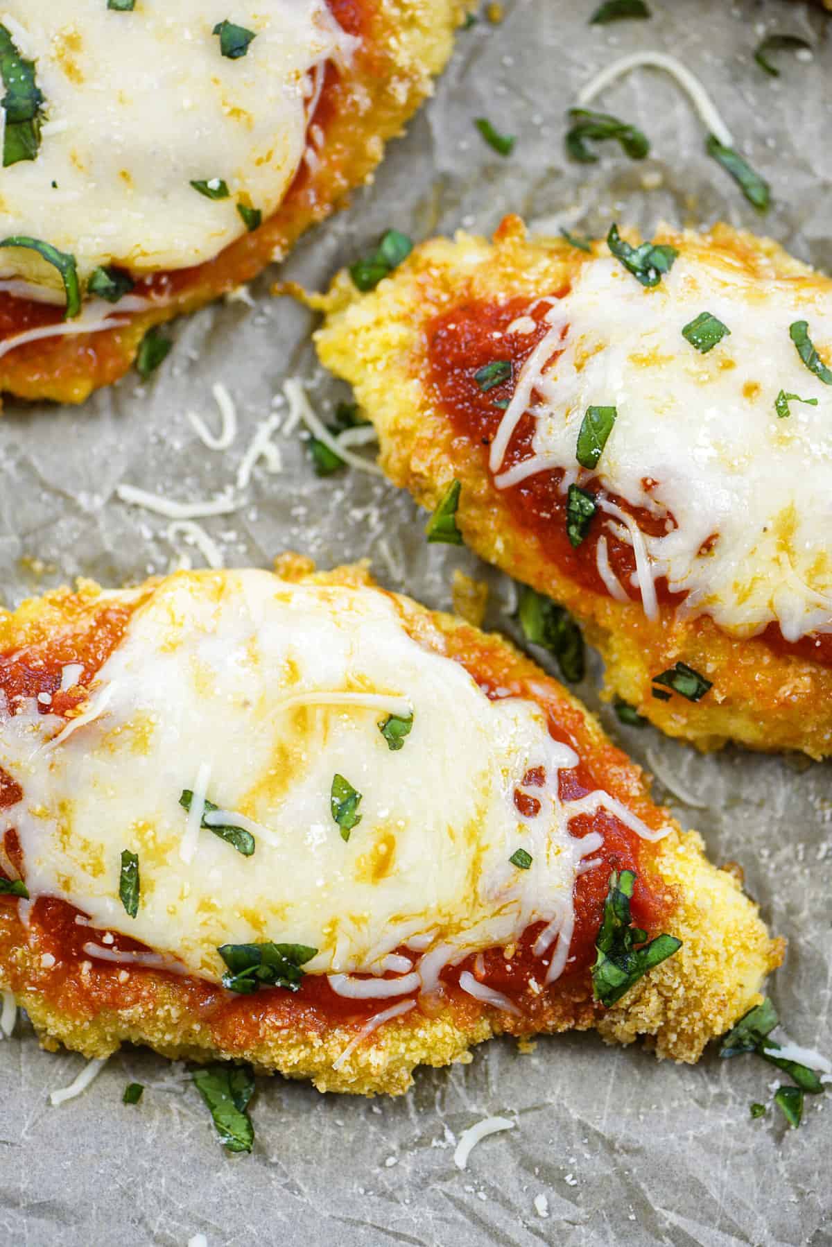 Overhead view of baked chicken Parmesan on sheet pan.