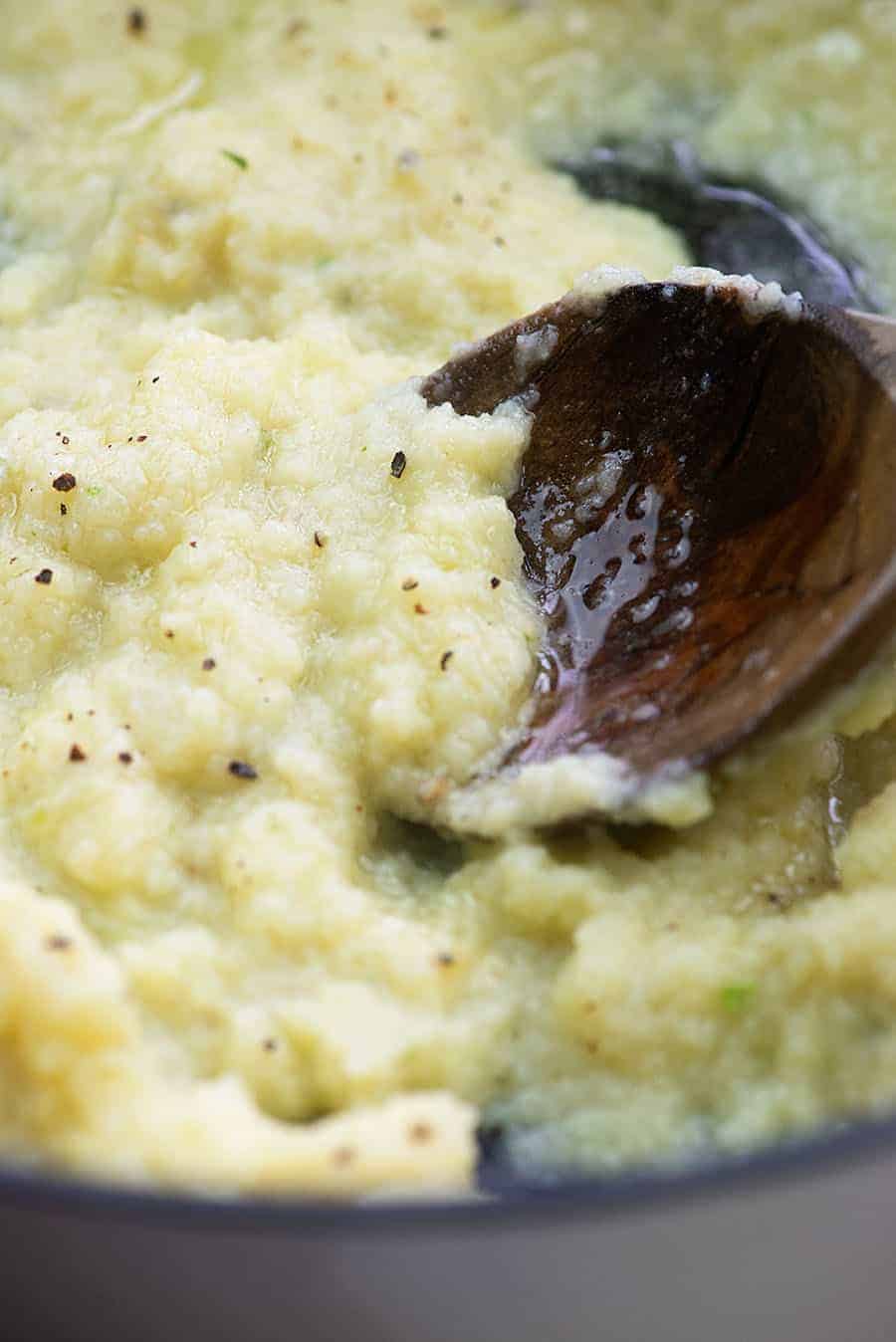 wooden spoon dipping into mashed cauliflower