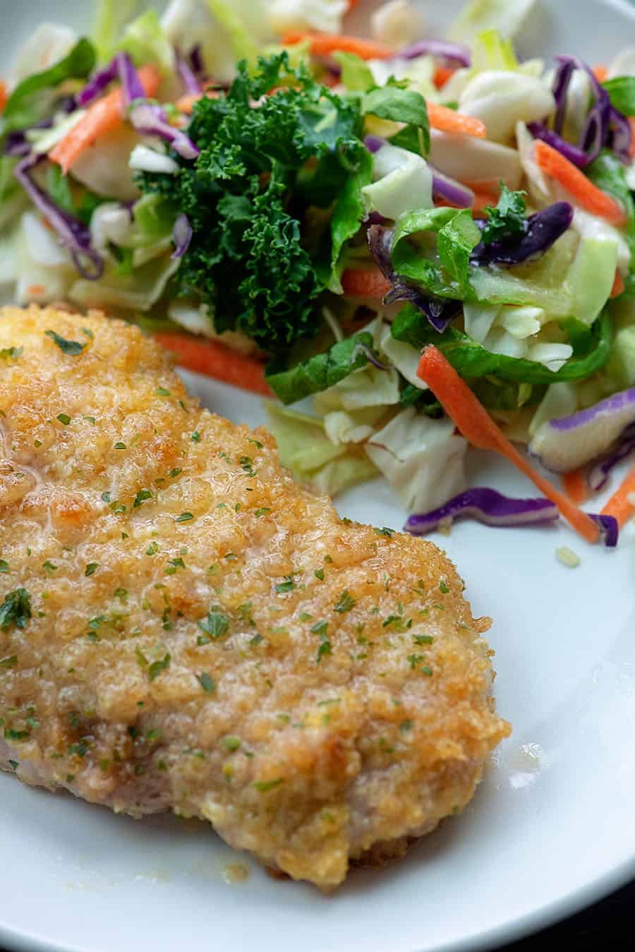 Baked pork chop and salad on a white plate