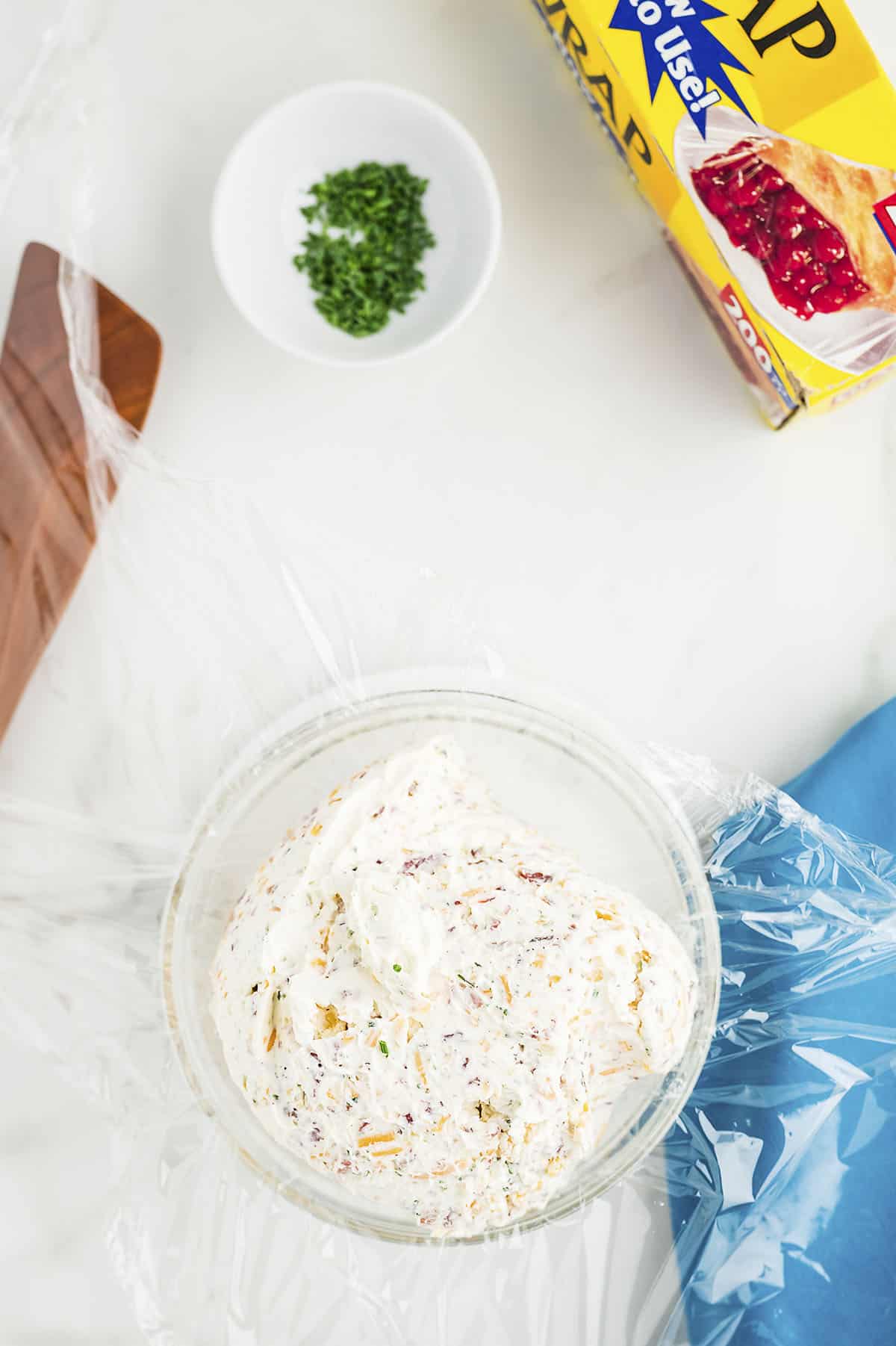 Cheese mixture laying on plastic wrap to show how to shape it into a ball.