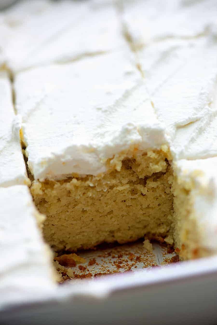 cream cake in a baking pan with one piece missing