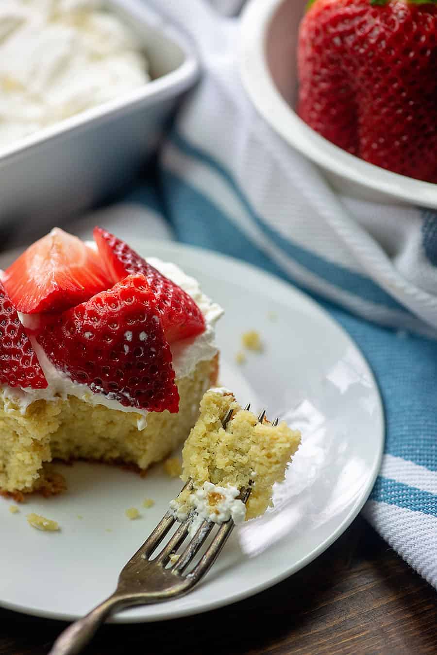 piece of cream cake with a bite out of it on a white plate