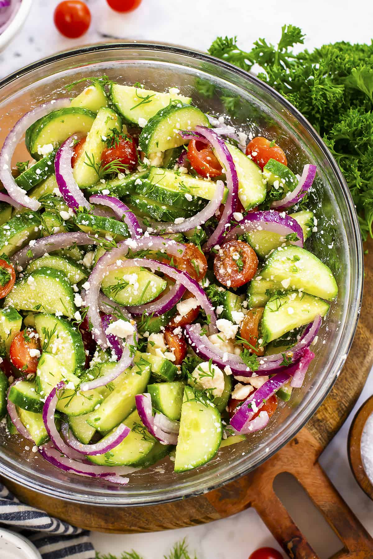 Overhead view of cucumber tomato feta salad in glass mixing bowl.