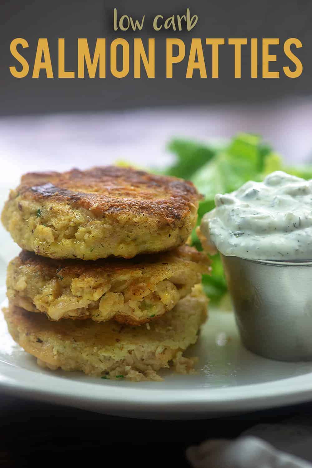 Low carb salmond patties on a plate with tartar sauce.