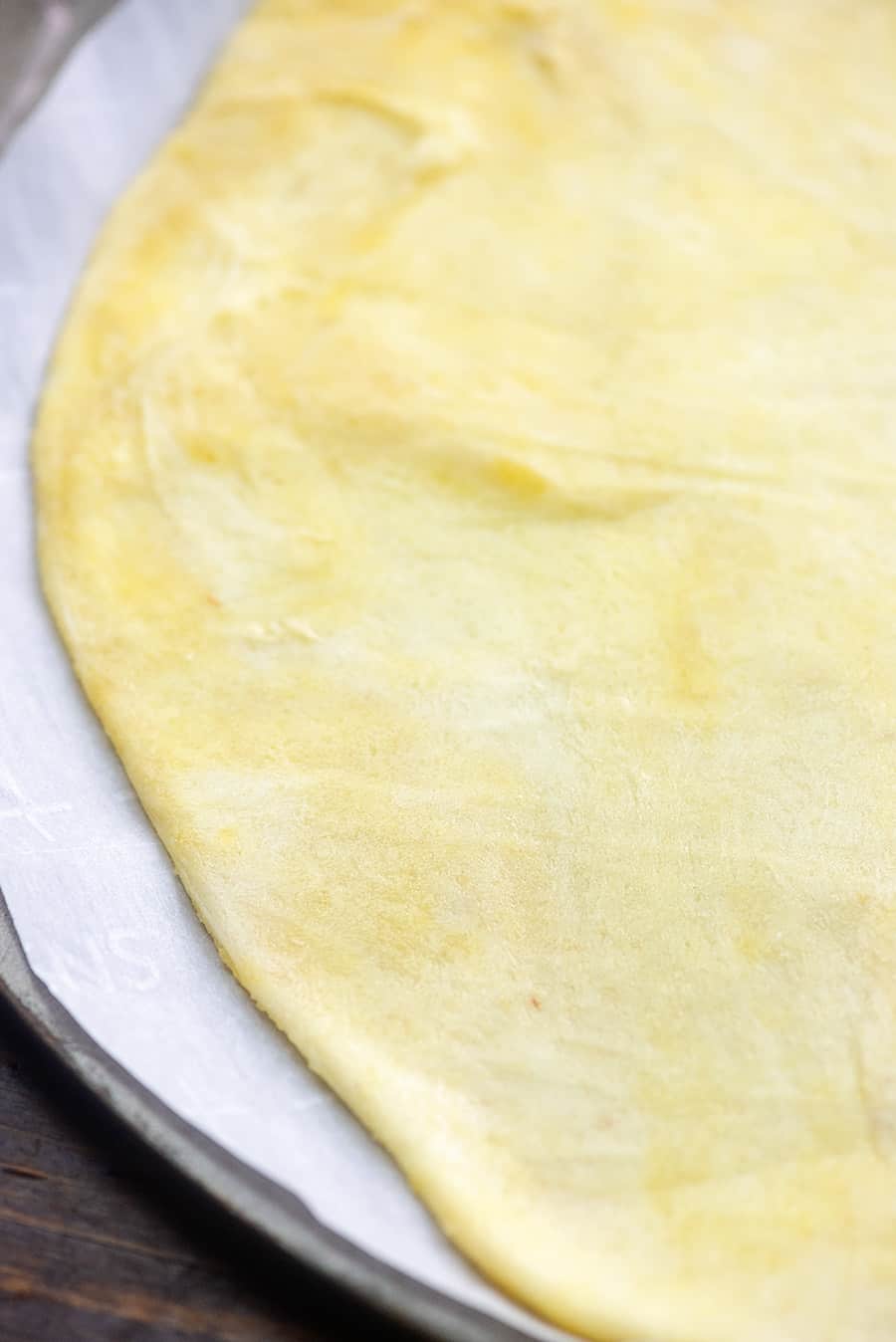 A close up of pizza dough rolled out on a pizza pan