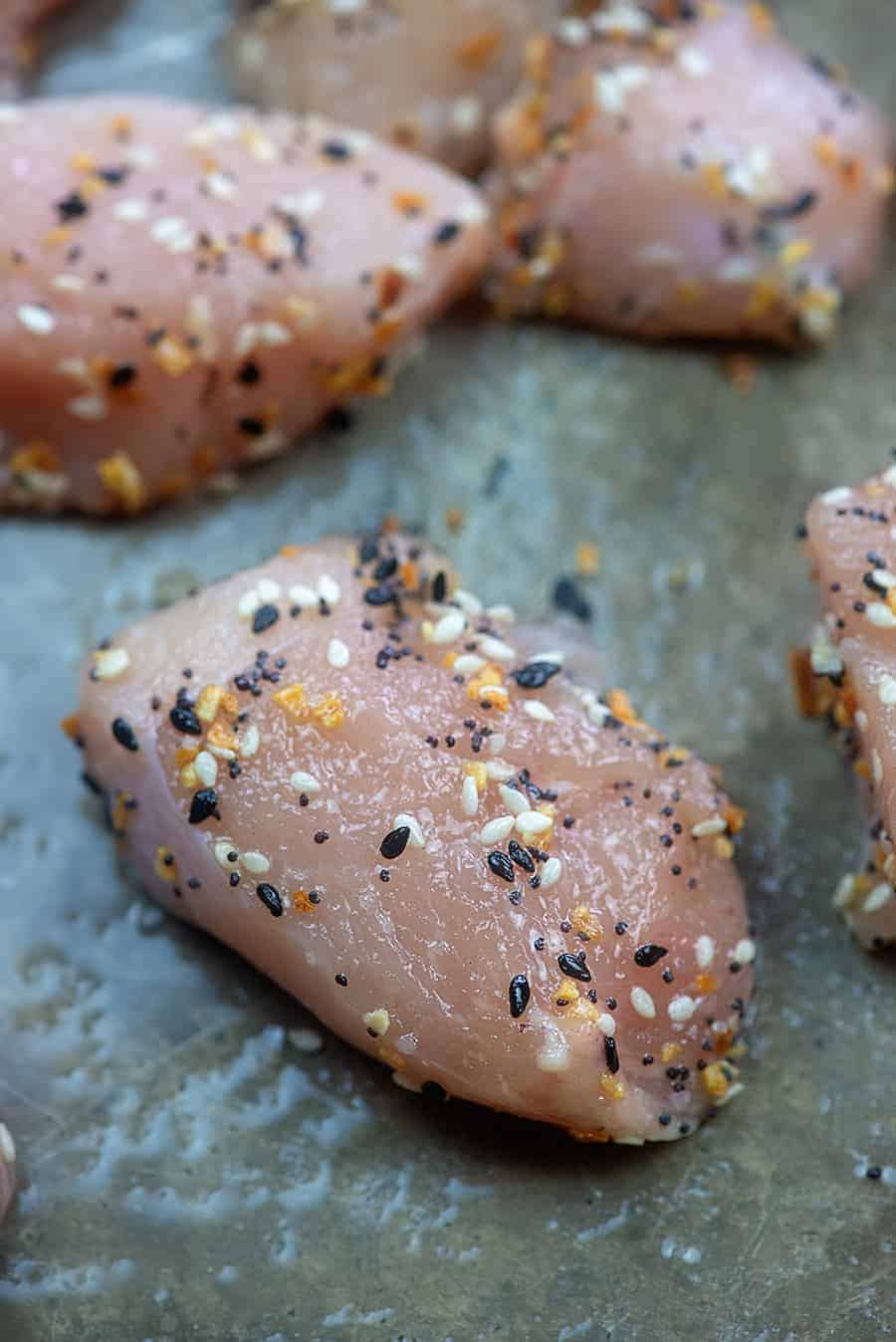A close up of raw seasoned piece of chicken breast
