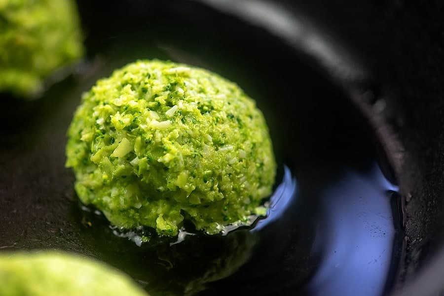 A close up of a broccoli fritters cooking in oil