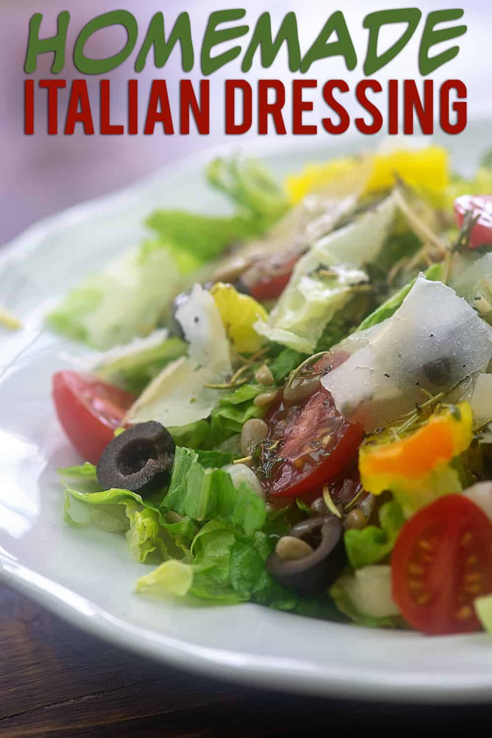 tomatoes, lettuce, cheese, and black olives on a white plate