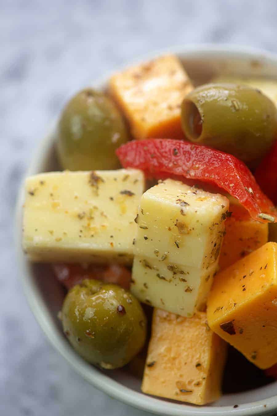 A close up of a bowl of cheese and olives