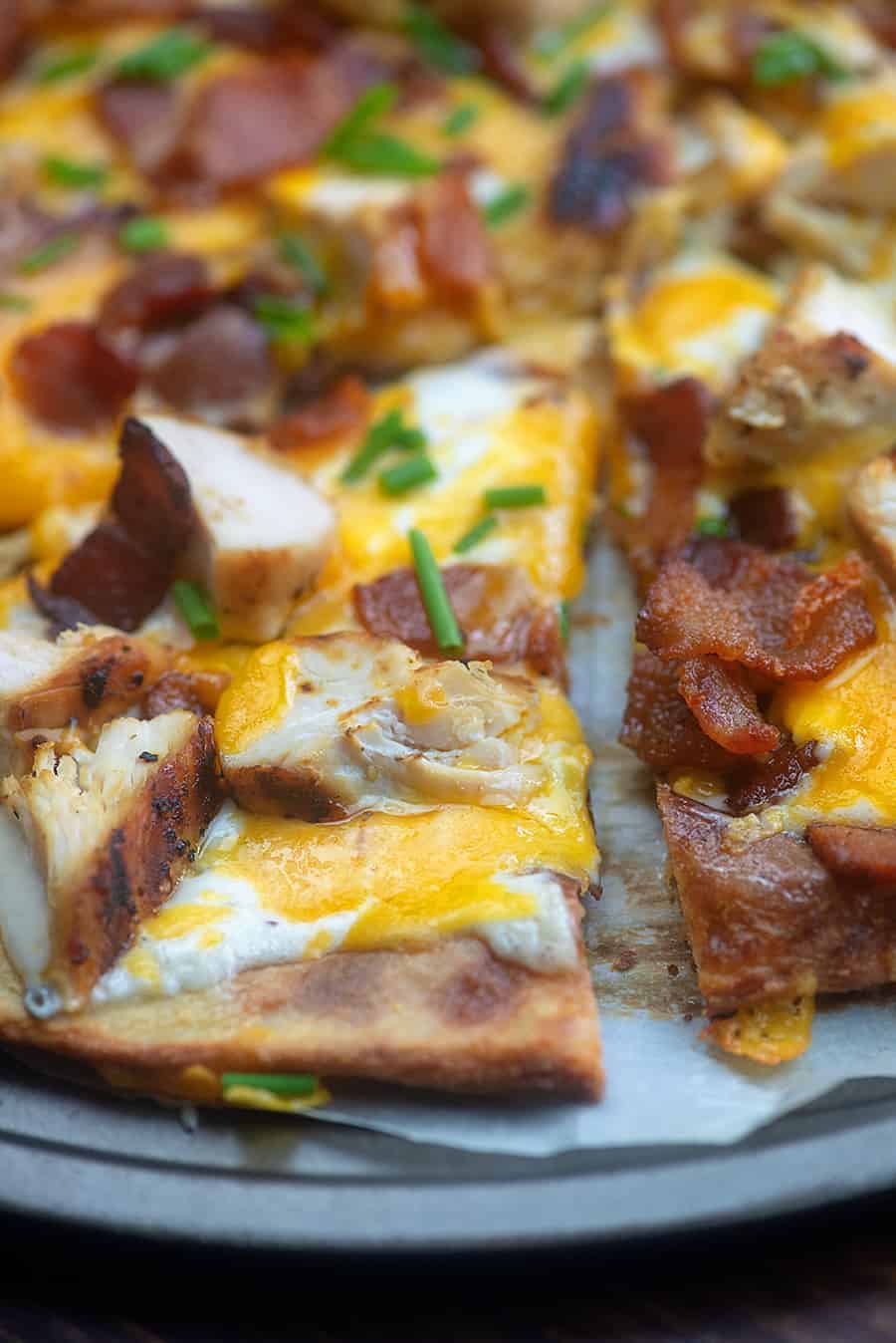 A close up of a slice of chicken bacon ranch pizza on a pizza pan.