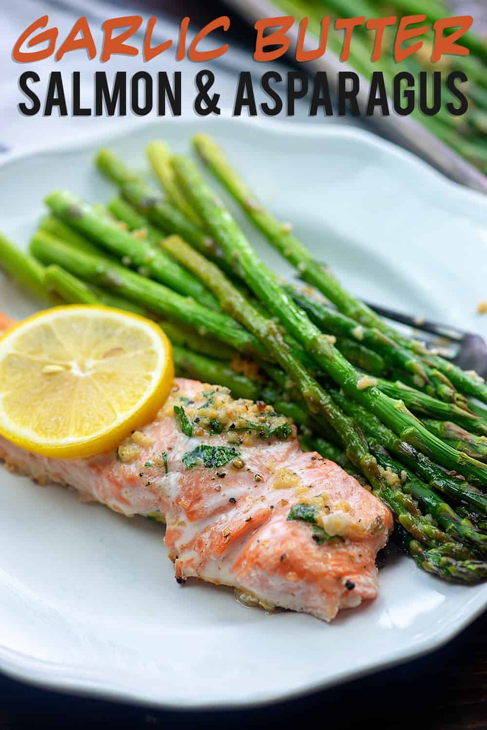 Garlic butter salmon and asparagus on a white plate.