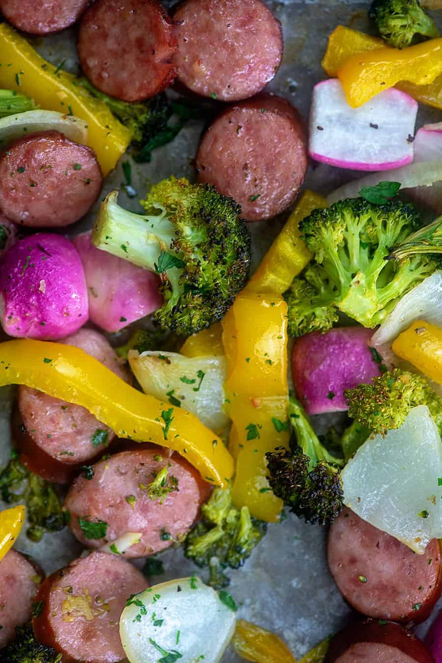 A close up of various vegetables and smoked sausages.