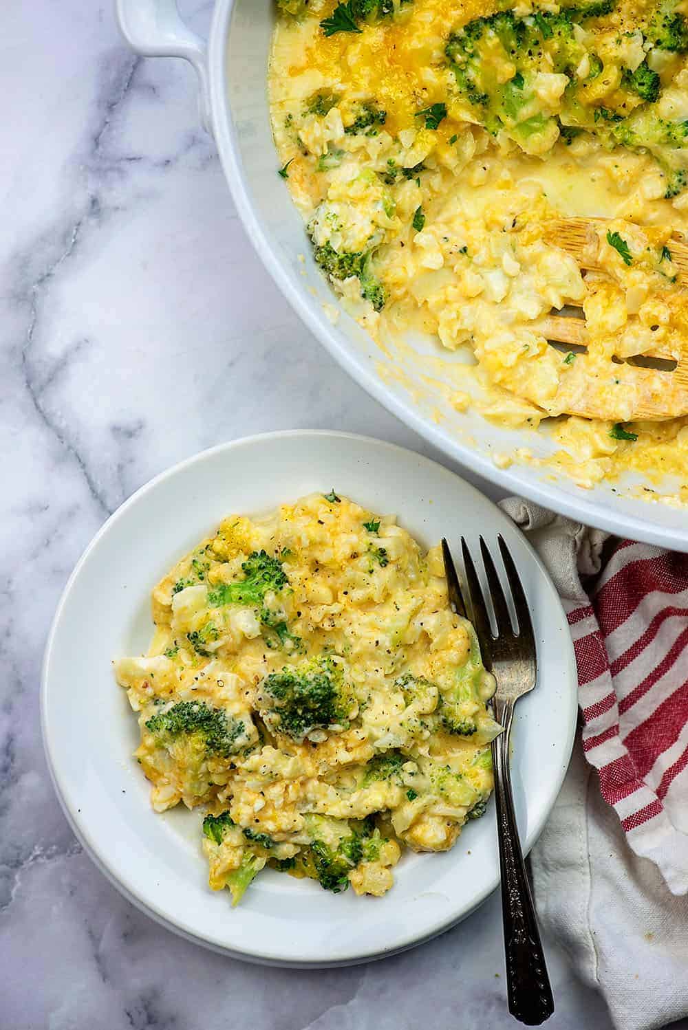 small white plate of broccoli and cheese next to a white pot of broccoli and cheese