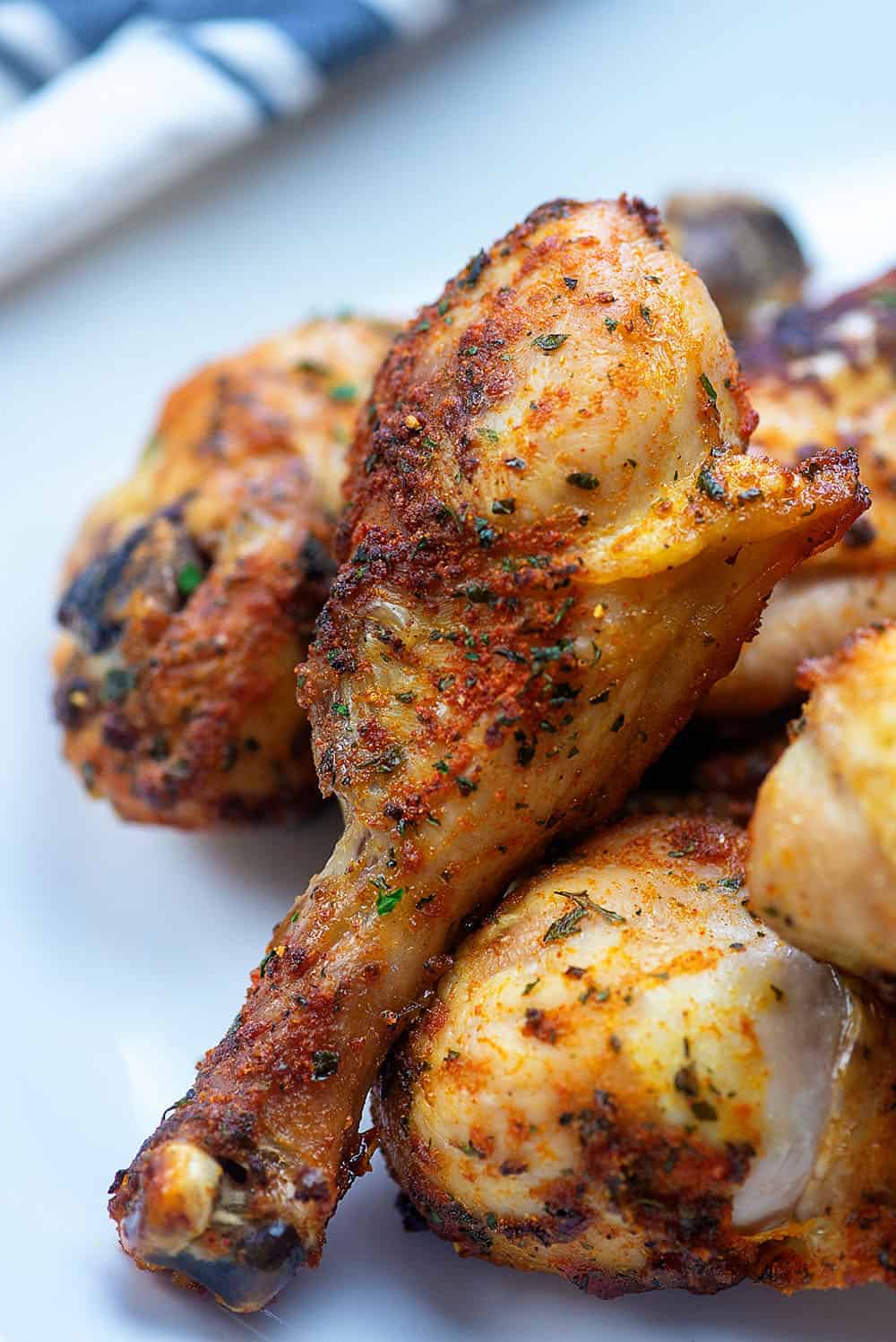 Stacked up chicken drumsticks on a white plate.