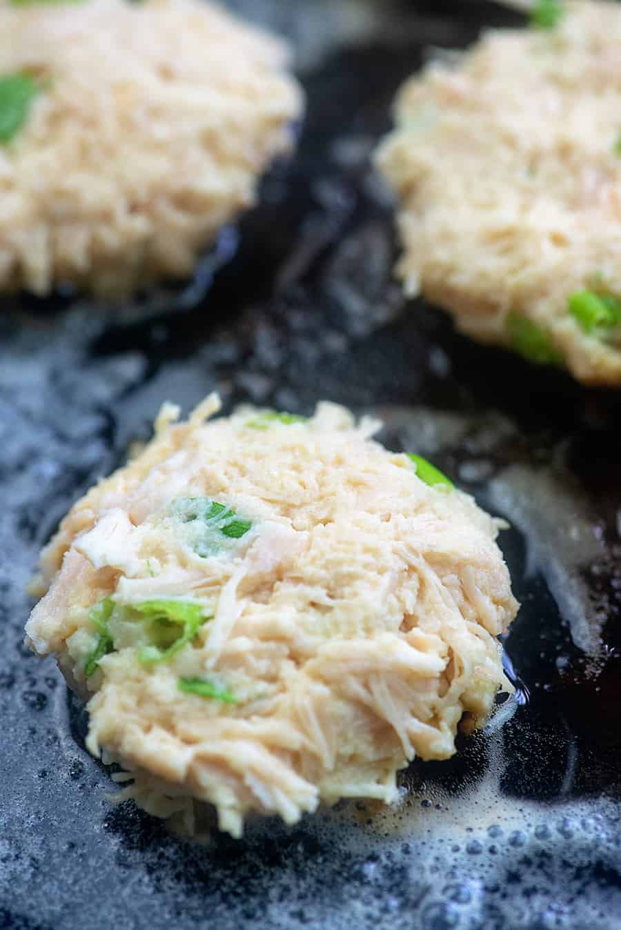 chicken patties simmering in a cast iron skillet