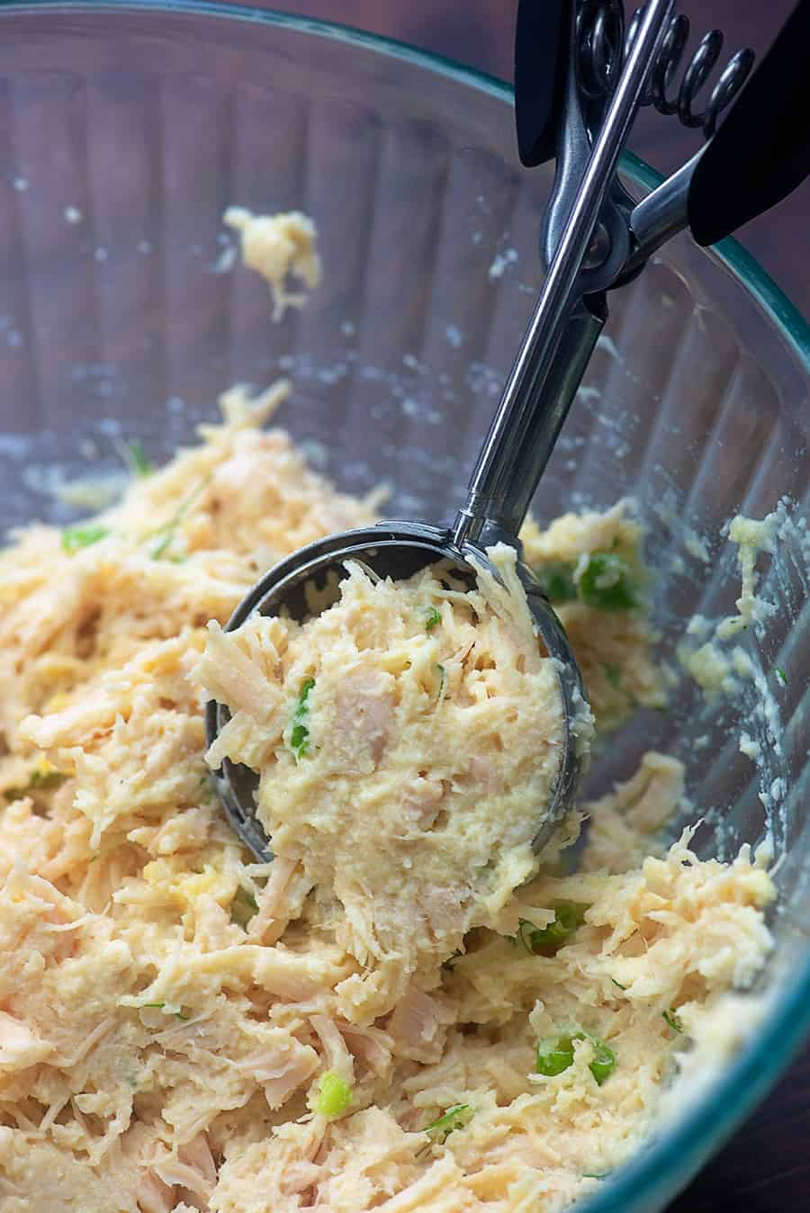 scooping raw chicken patty mixture from a glass bowl