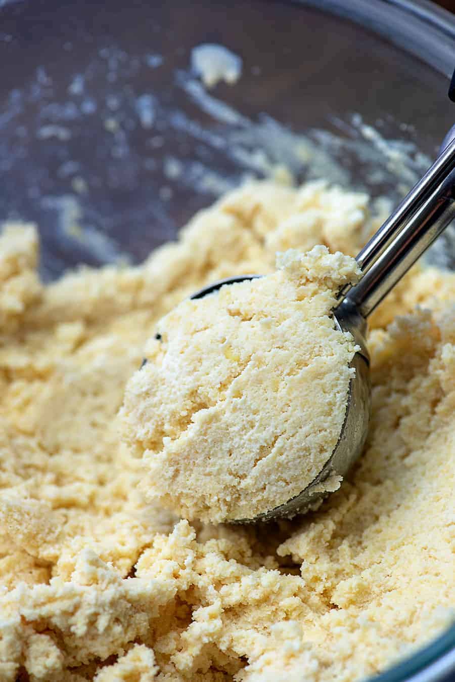 scooping biscuit dough from a glass bowl