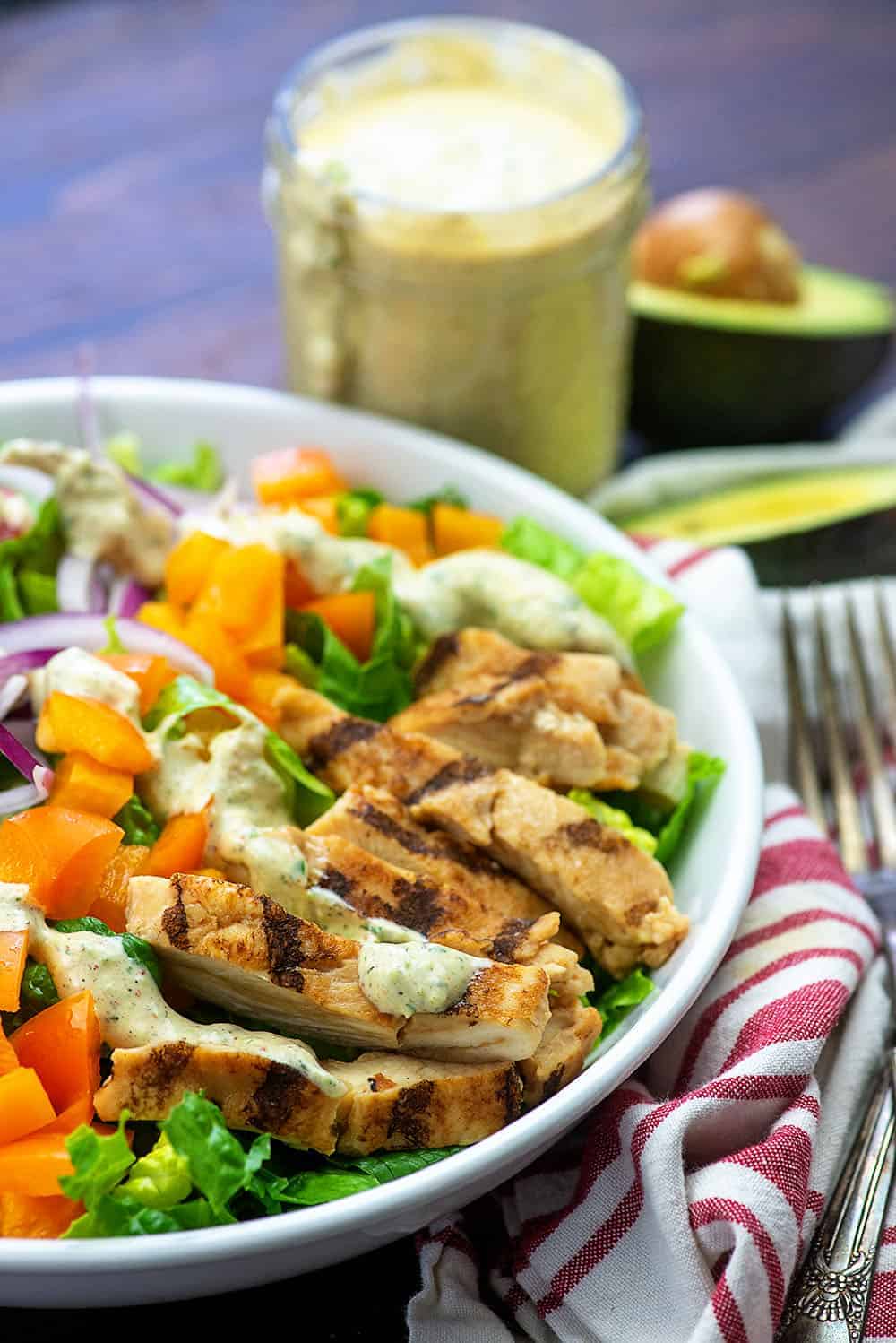 bowl of salad topped with avocado dressing.