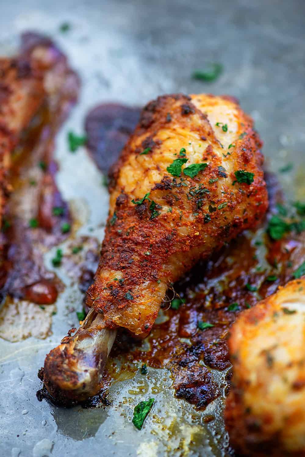 A close up of a cooked chicken drumstick on a baking sheet