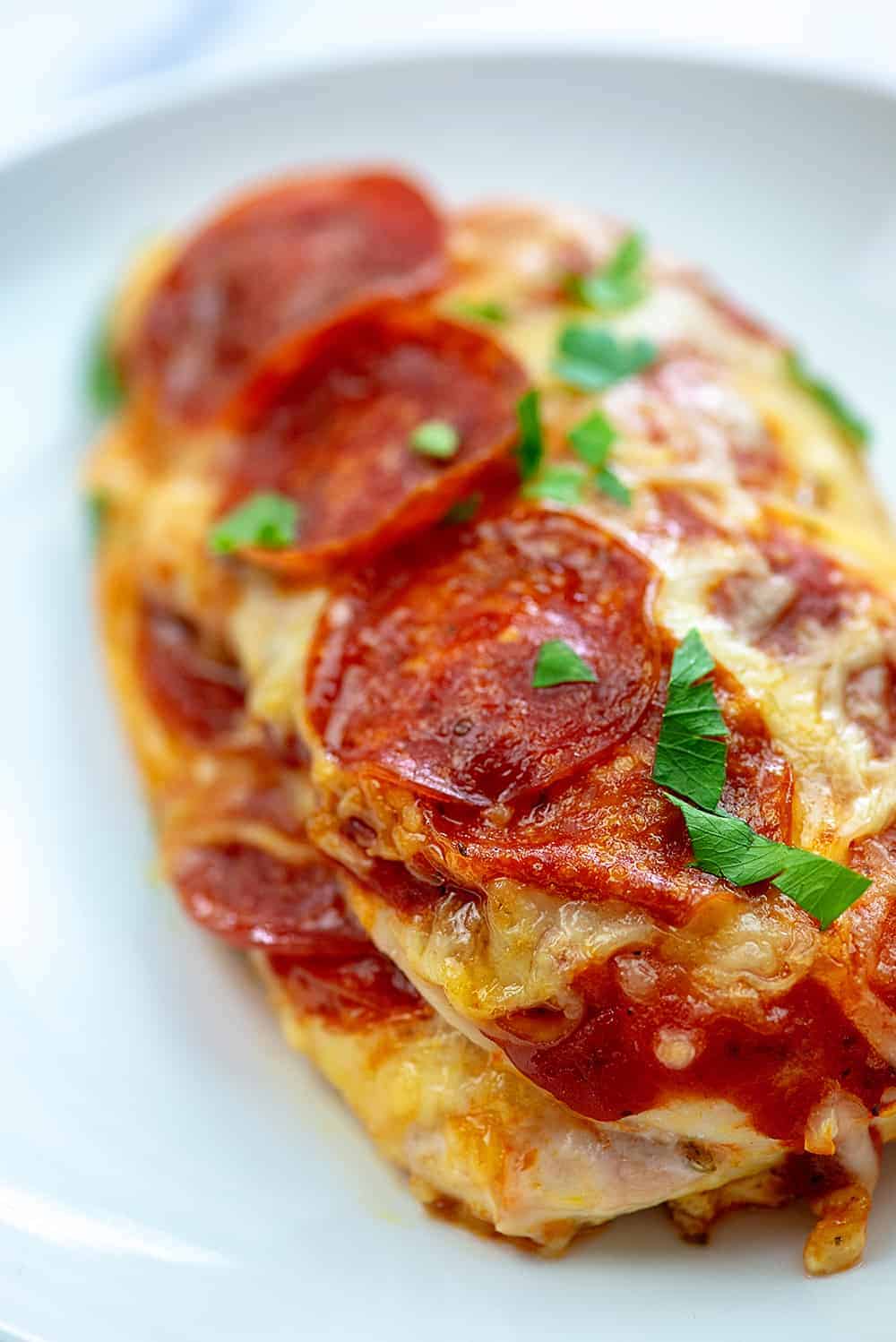 two pieces of pizza stuffed chicken stacked up on a white plate