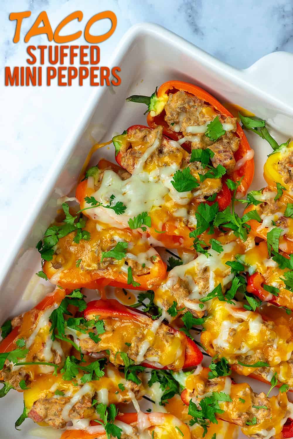 taco stuffed peppers topped with cheese in a white baking pan