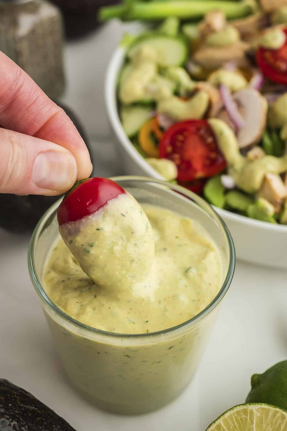 Mini sweet pepper being dunked in avocado salad dressing.