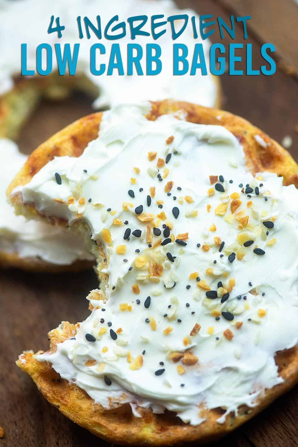 A low carb bagel topped with cream cheese and seasoning with a bite taken out of it.