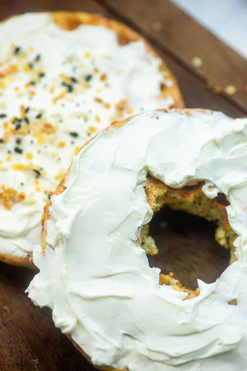 A low carb bagel topped with cream cheese and seasoning with a whole cut out of the middle.