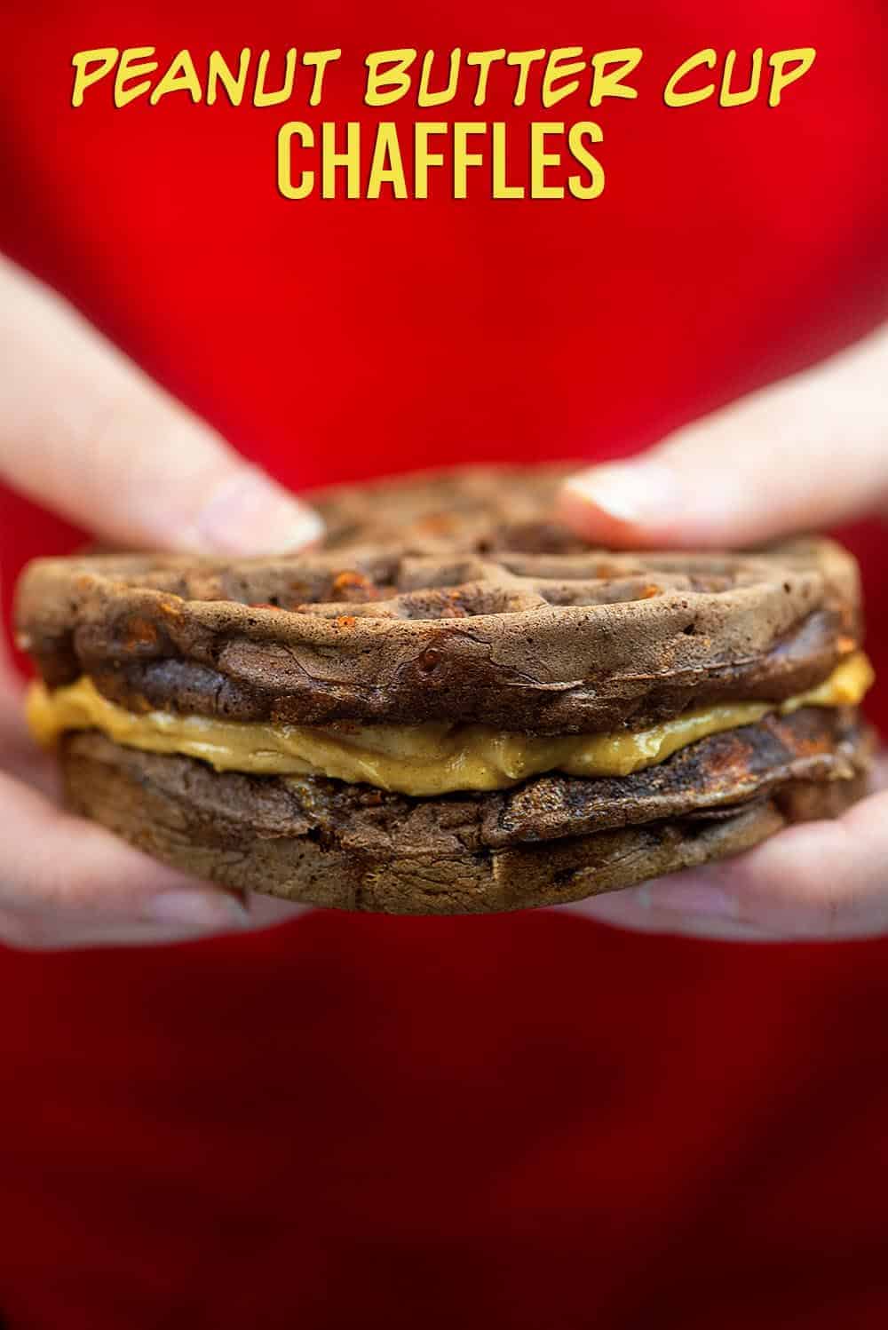 two hands holding chocolate waffles with peanut butter in the middle