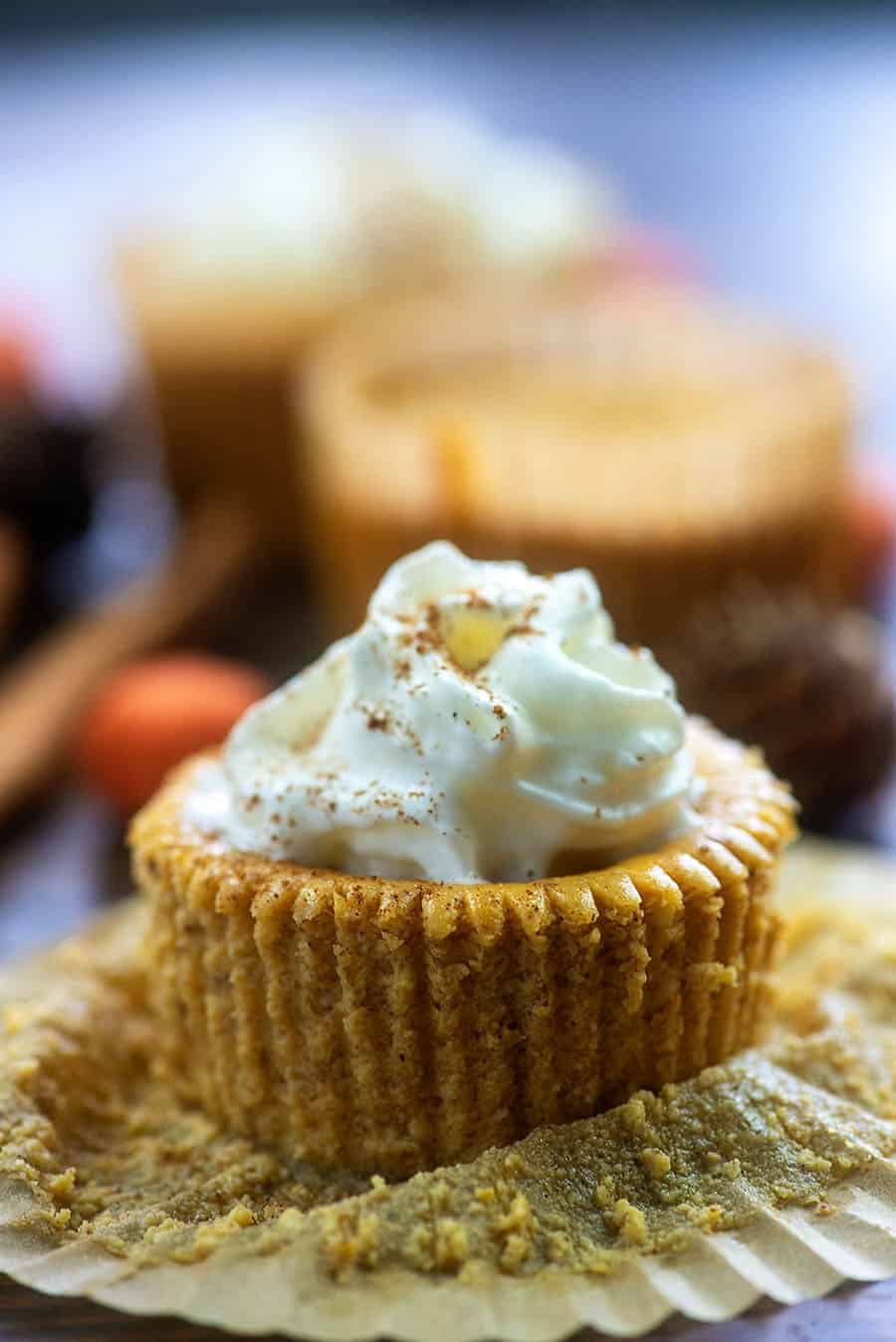 A close up of pumpkin cheesecake with a cupcake wrapper unfolding around it.