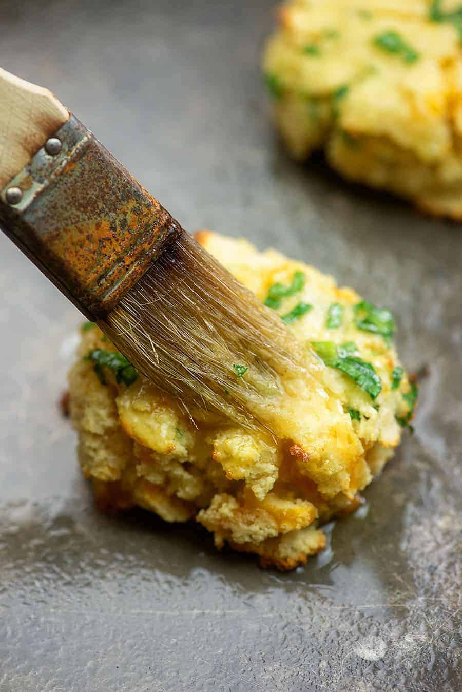 brushing butter on a cheddar biscuit