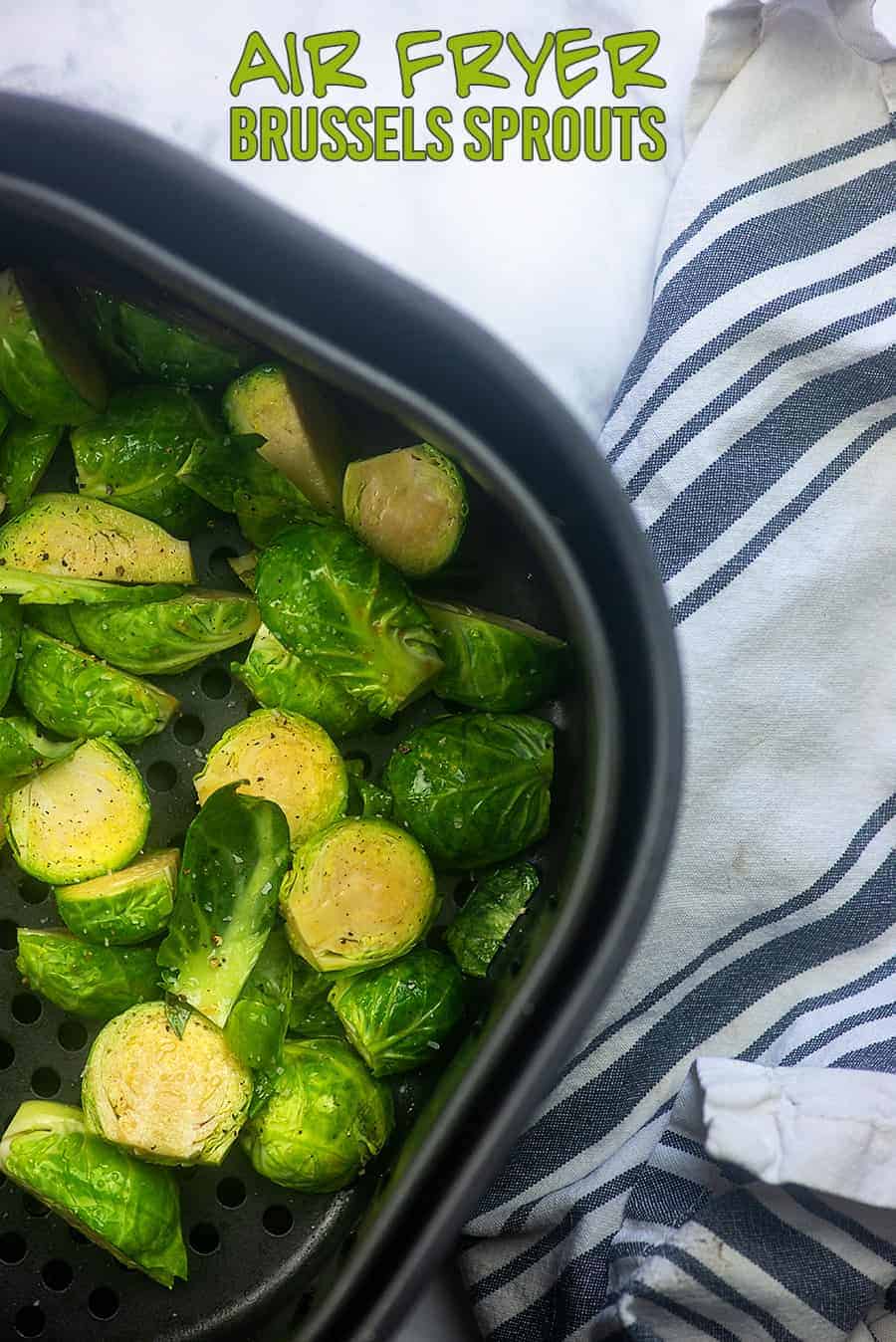 brussel sprouts in an air fryer pan on a blue and white dish towel