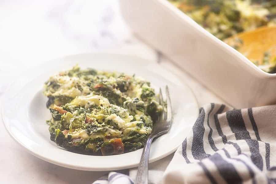 cheesy spinach souffle on a white plate with a fork