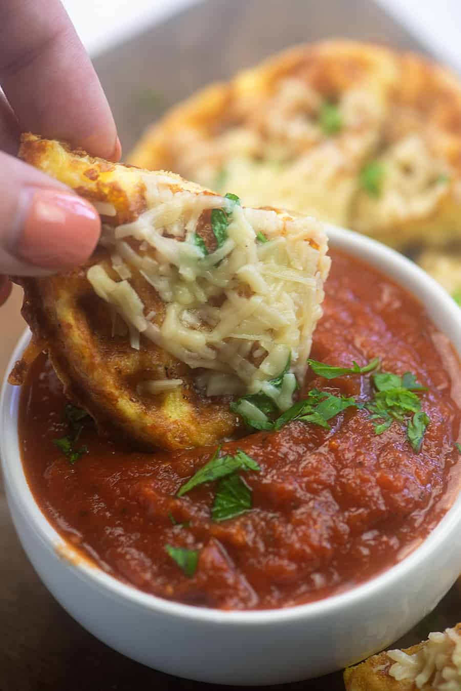 piece of garlic chaffle dipped in a tomato sauce cup