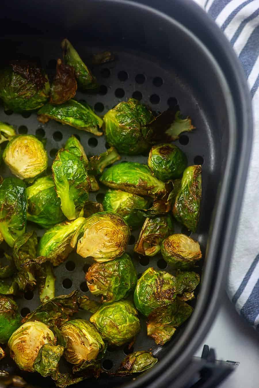 A bunch of Brussel sprouts in an air fryer basket