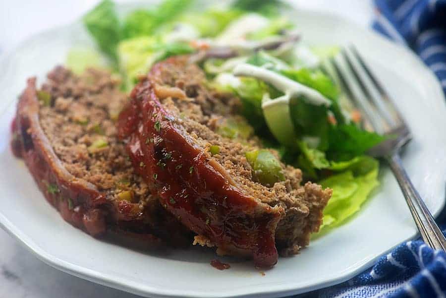 Two pieces of meatloaf on a white plate.