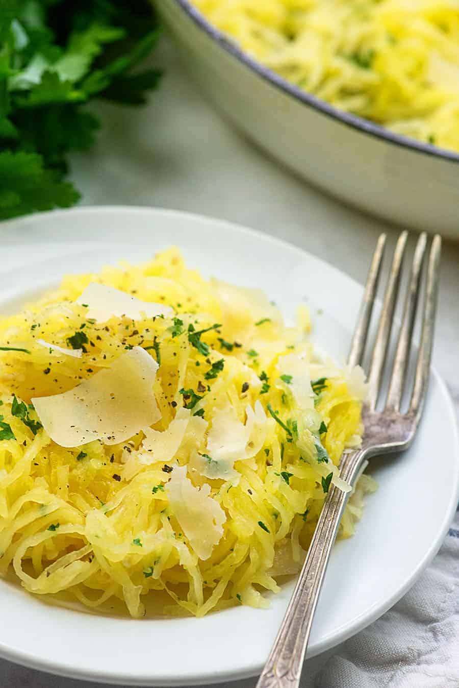 Garlic parmesan spaghetti squash on a white plate with a fork.