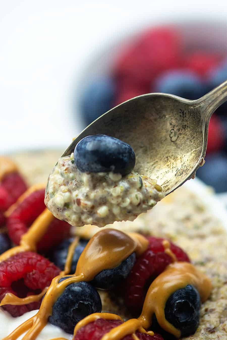 A close up of a blueberry and oatmeal on an old silver spoon.