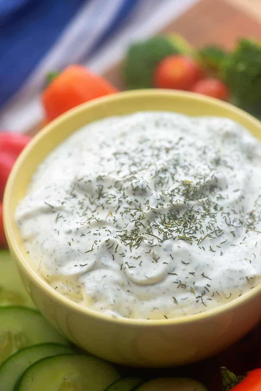 A bowl of dill veggie dip surrounded by vegetables