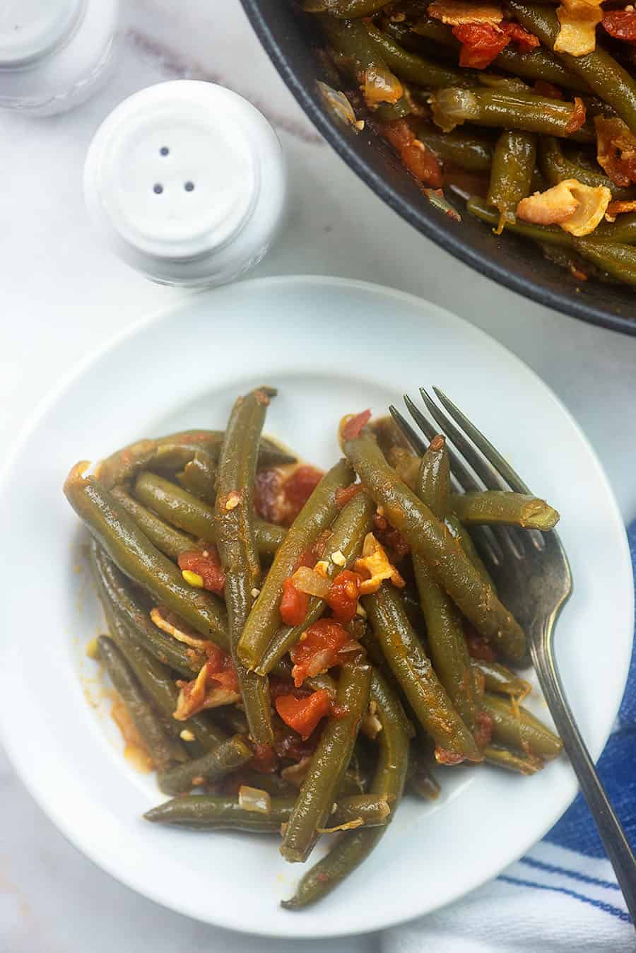 Overhead view of green beans on a white plate.