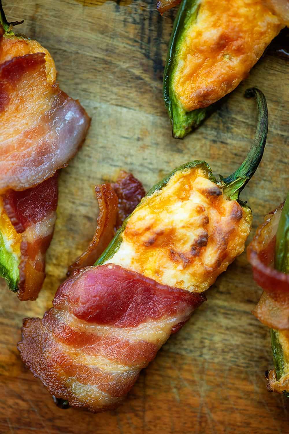 keto jalapeno poppers wrapped in bacon on a cutting board