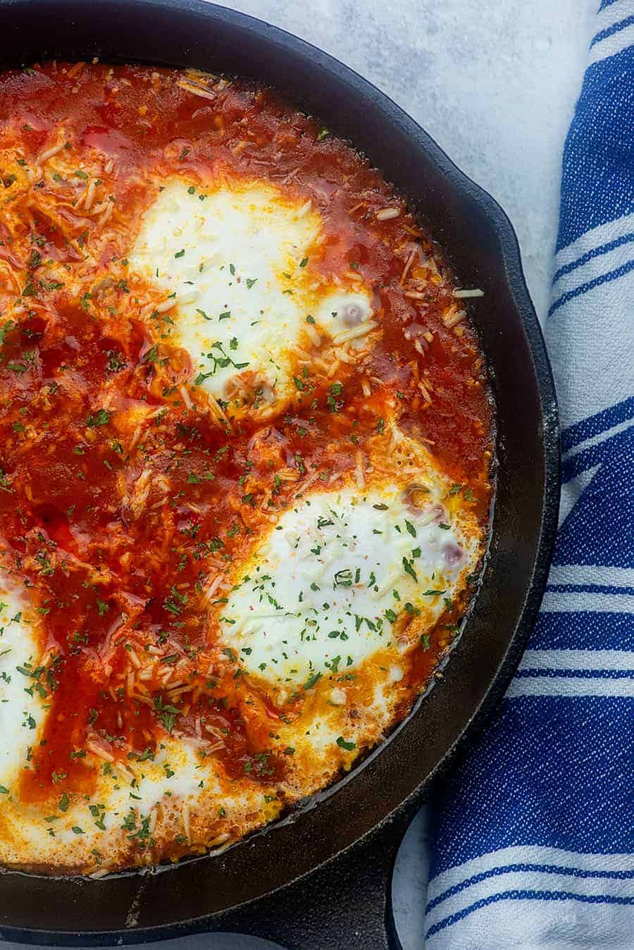 eggs in tomato sauce cooking in a cast iron skillet