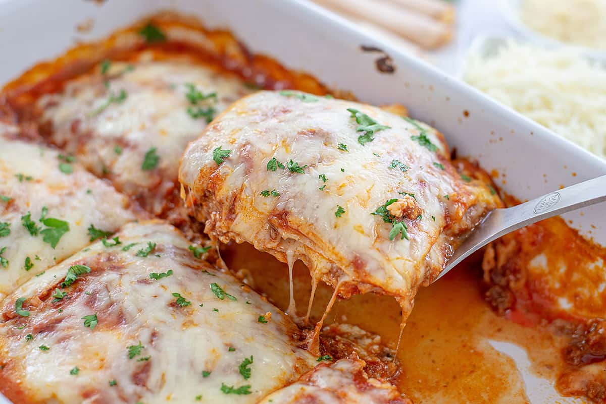 lasagna being removed from baking dish.