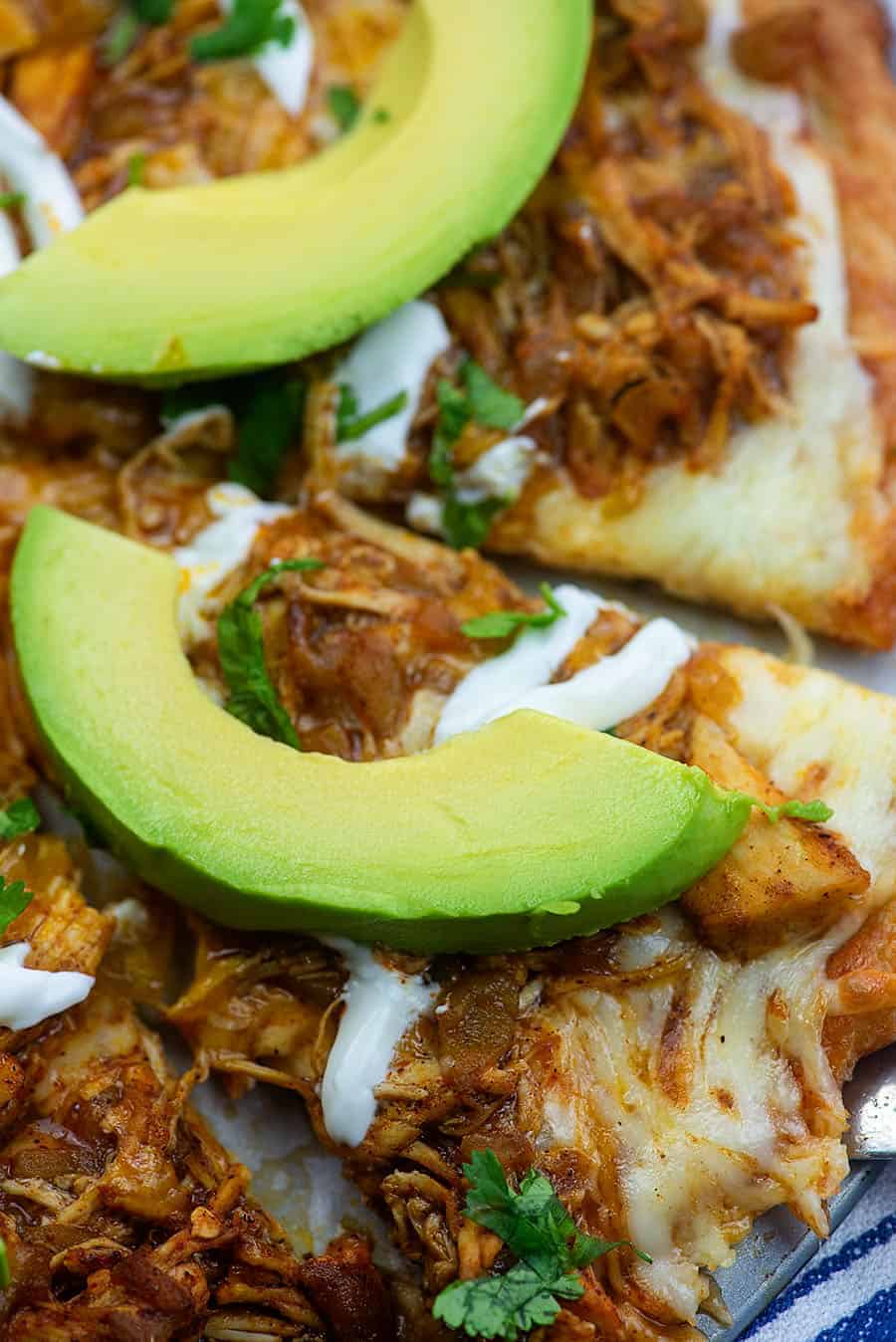 cut up enchilada pizza with avocado slices on every piece