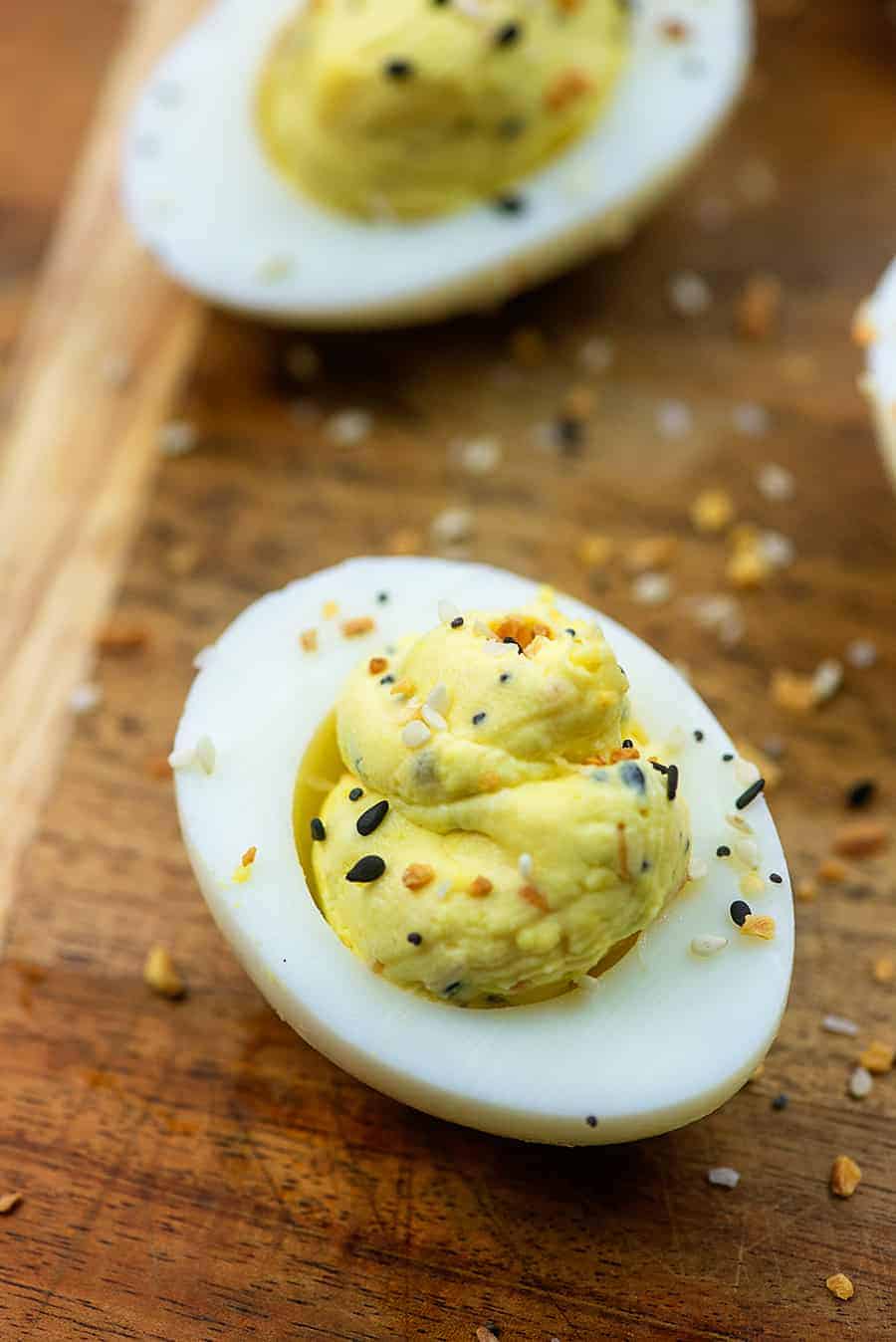 A close up of an everything bagel seasoned deviled egg on a cutting board.