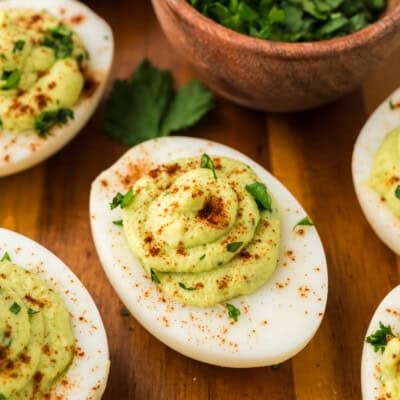 Avocado deviled eggs on wooden cutting board.