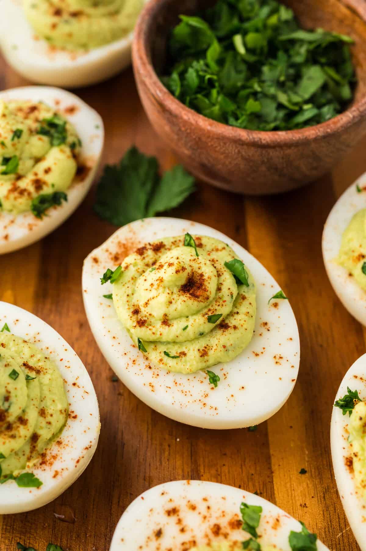 Avocado deviled eggs on wooden cutting board.