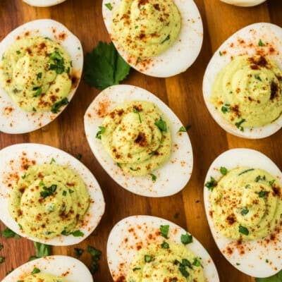 Overhead view of avocado deviled egg recipe on wooden board.